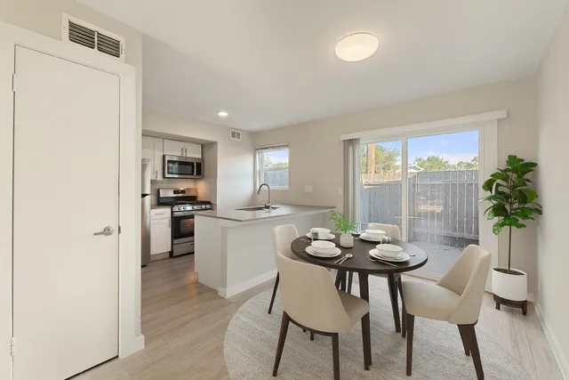 a kitchen with a dining table chairs and refrigerator