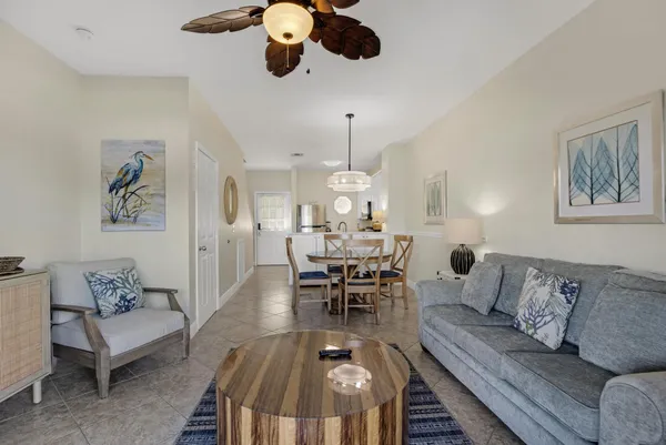 a living room with furniture kitchen view and a chandelier