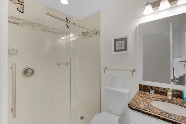 a bathroom with a granite countertop shower sink vanity and mirror