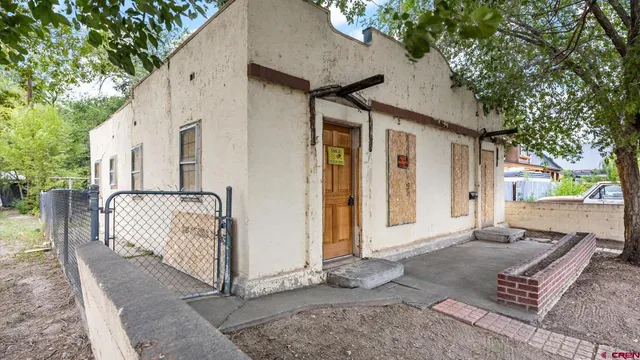 a view of a house with wooden fence and large trees