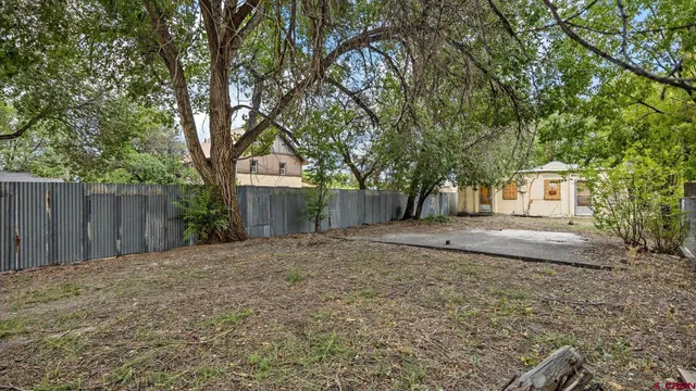 a view of a backyard with large trees and wooden fence