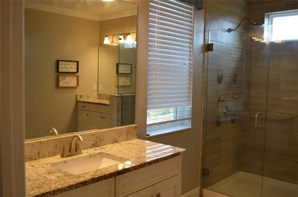 a bathroom with a granite countertop sink a mirror and shower
