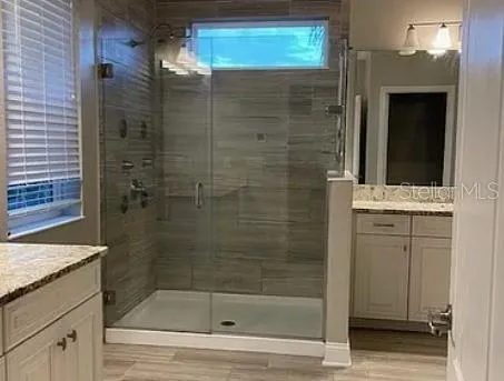 a bathroom with a granite countertop sink a mirror and shower