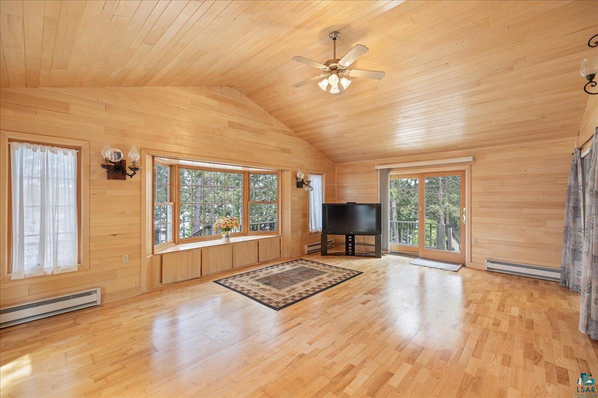 1804 North Bay Road Ely, MN 55731 - Photo 10 of 37 Unfurnished living room featuring light hardwood / wood-style flooring, wood ceiling, a baseboard radiator, wood walls, and ceiling fan
