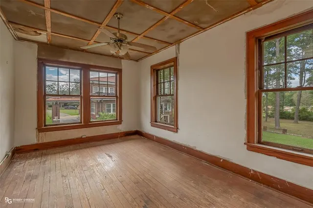 a view of an empty room with a window and wooden floor
