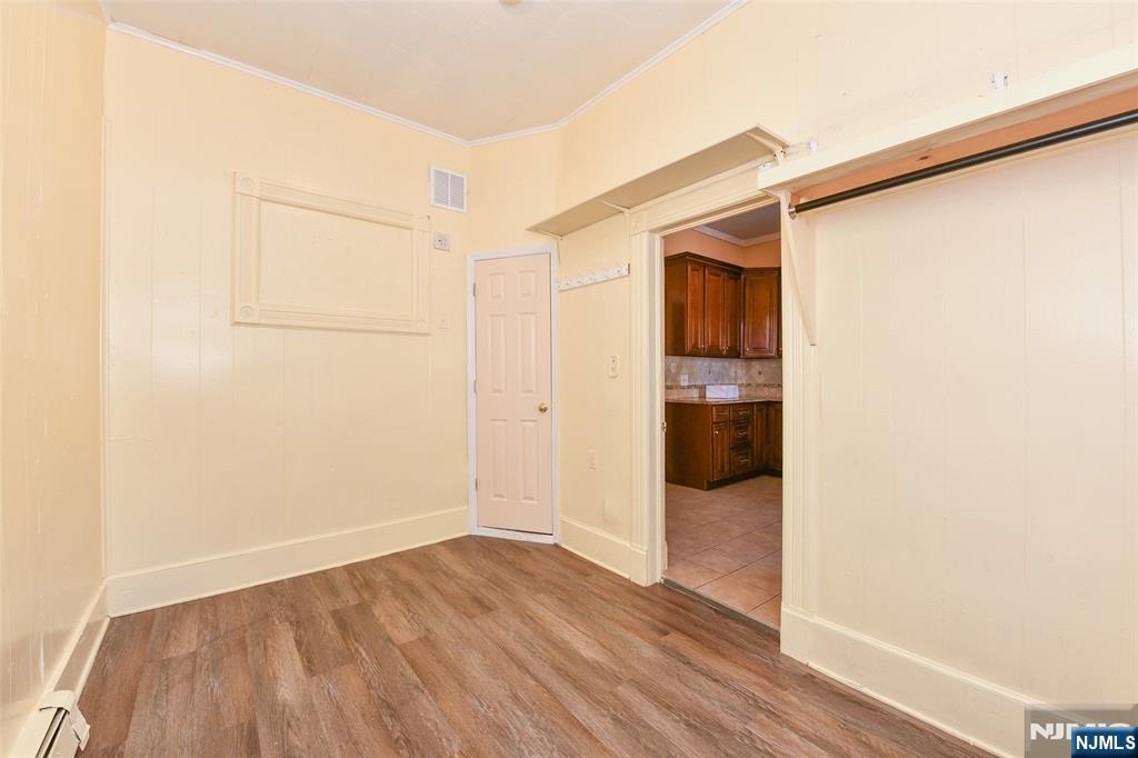 208 4th Street Passaic, NJ 07055 - Photo 7 of 28 an empty room with wooden floor and windows