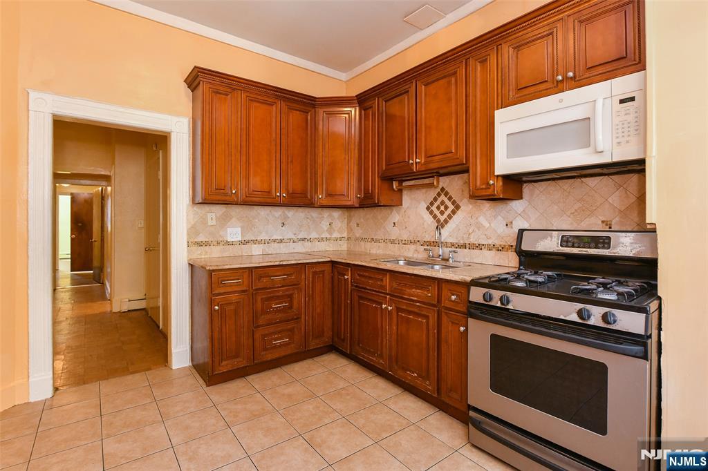 208 4th Street Passaic, NJ 07055 - Photo 8 of 28 a kitchen with stainless steel appliances granite countertop a stove microwave and cabinets