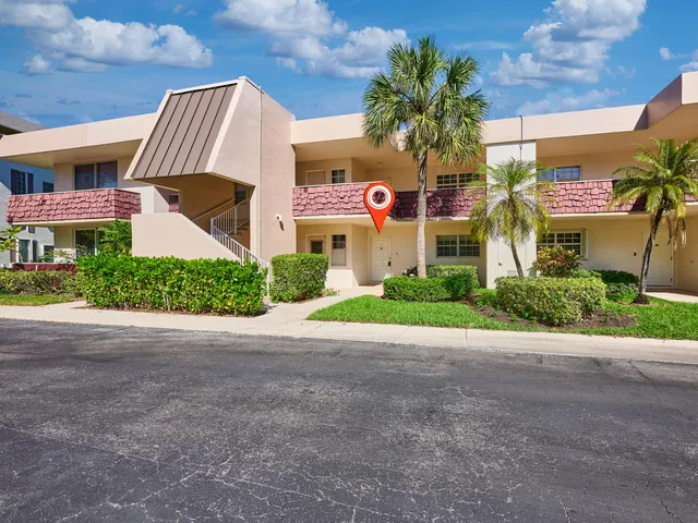 a front view of a building with garden and parking