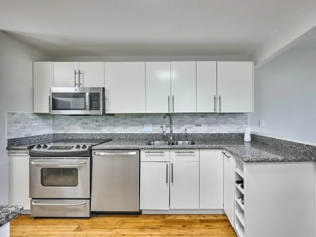 a kitchen with granite countertop white cabinets and stainless steel appliances
