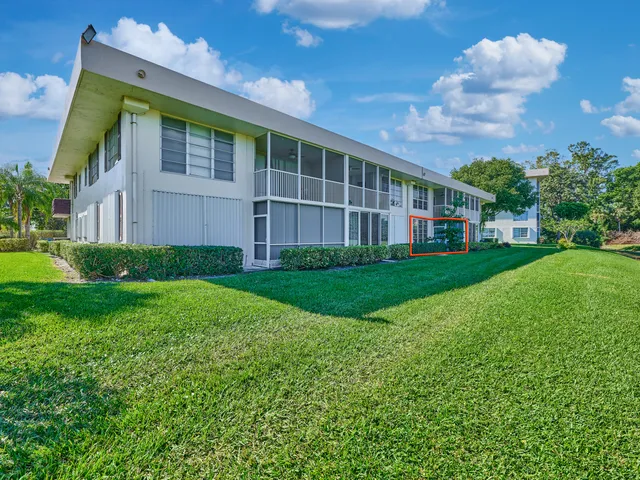 a view of an apartment with a big yard and large trees