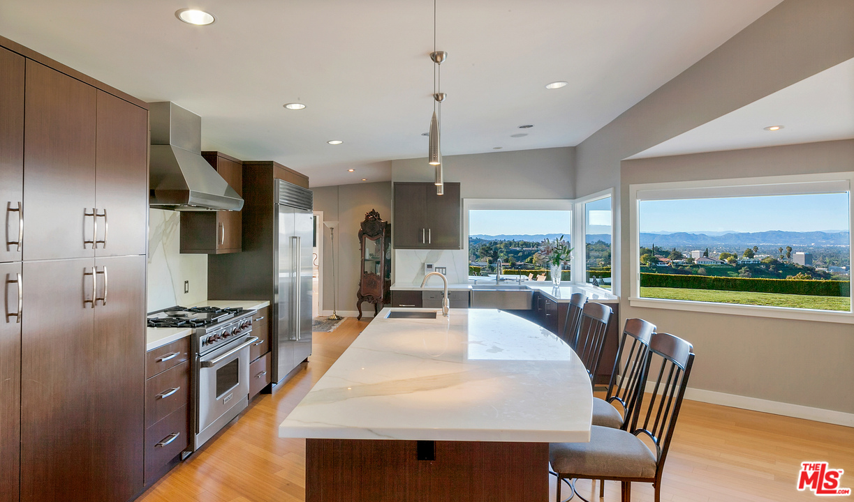 3921 Cody Road Sherman Oaks, CA 91403 - Photo 11 of 36 a kitchen with stainless steel appliances kitchen island granite countertop a stove a refrigerator a kitchen island a couches and a dining table with garden view