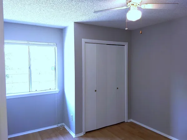 an empty room with a window and a chandelier fan