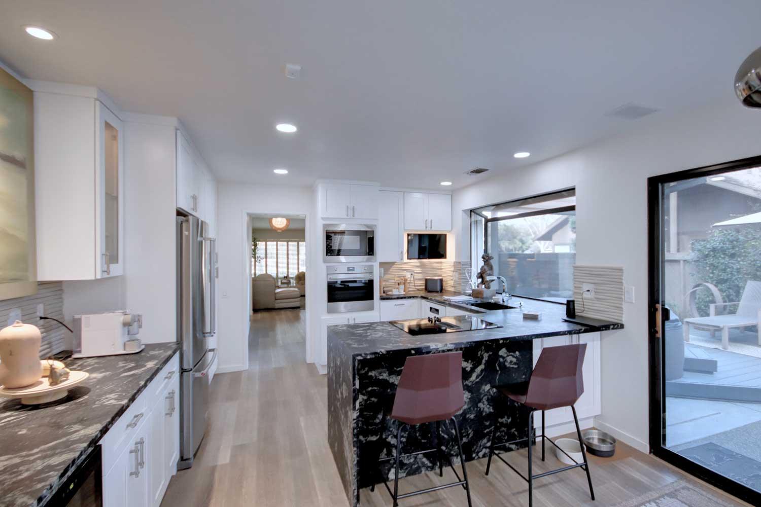a kitchen with stainless steel appliances kitchen island granite countertop a stove a refrigerator a sink dishwasher and a dining table with wooden floor