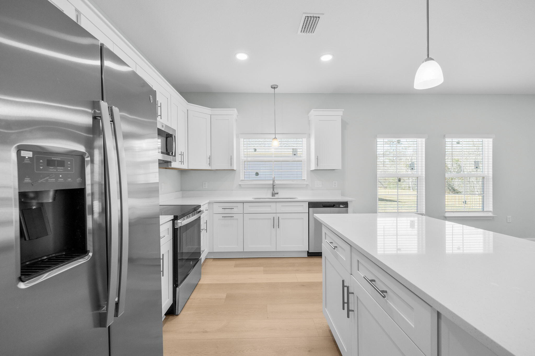 72 Riverwalk Circle Freeport, FL 32439 - Photo 5 of 34 a large kitchen with stainless steel appliances kitchen island granite countertop a refrigerator a sink dishwasher a stove and white cabinets with wooden floor