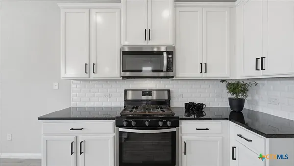 a kitchen with granite countertop white cabinets and black appliances