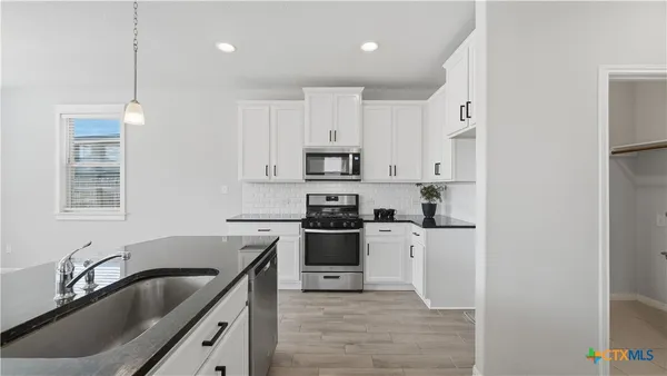 a kitchen with granite countertop white cabinets and stainless steel appliances