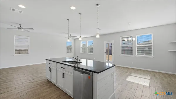 a kitchen with granite countertop a sink cabinets and wooden floor