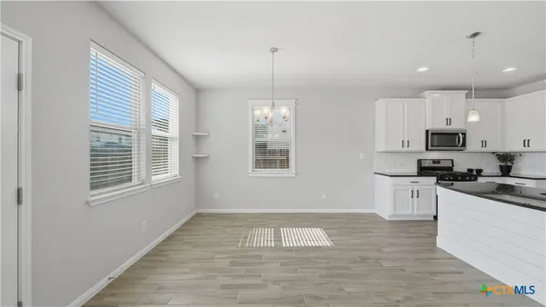 a kitchen with stainless steel appliances granite countertop a stove a sink and white cabinets