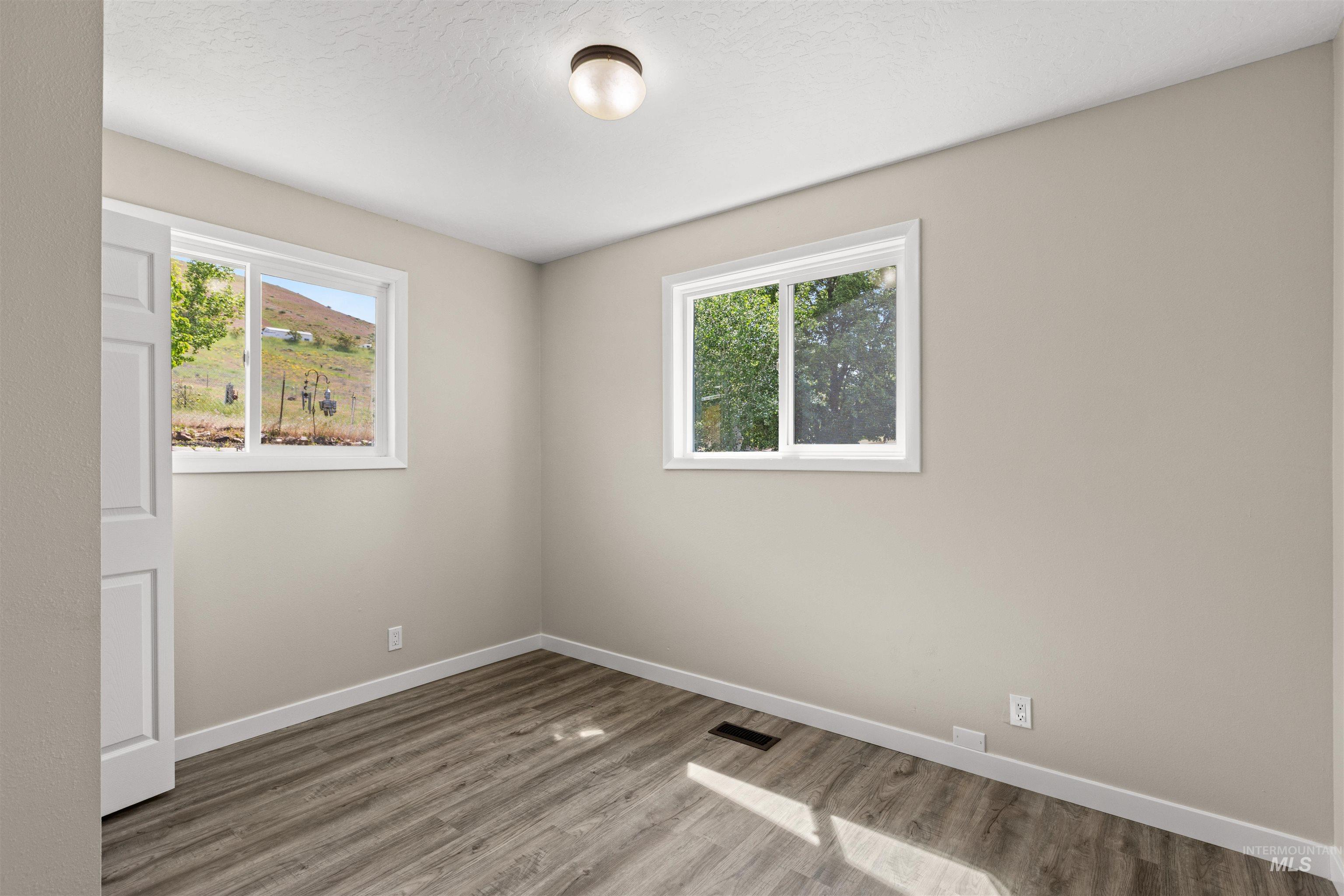 12184 Hill Road Payette, ID 83661 - Photo 26 of 35 Room featuring two windows, wood-finish flooring, light neutral-toned walls, white trim, and a flush mount ceiling light