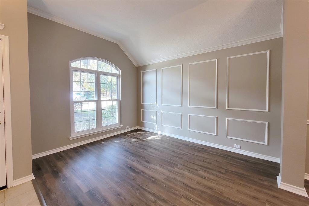 1604 Knoll Ridge Circle Corinth, TX 76210 - Photo 10 of 37 Spacious room featuring vaulted ceilings, an arched window, wood-finish flooring, crown molding, and decorative wall paneling