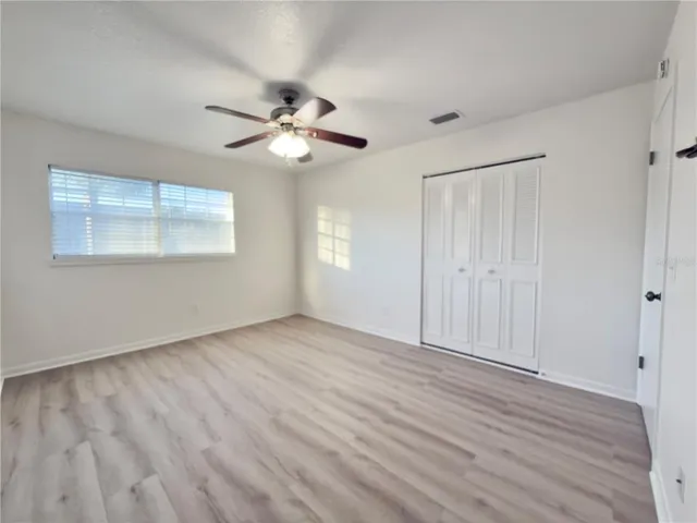 a view of empty room with wooden floor and fan
