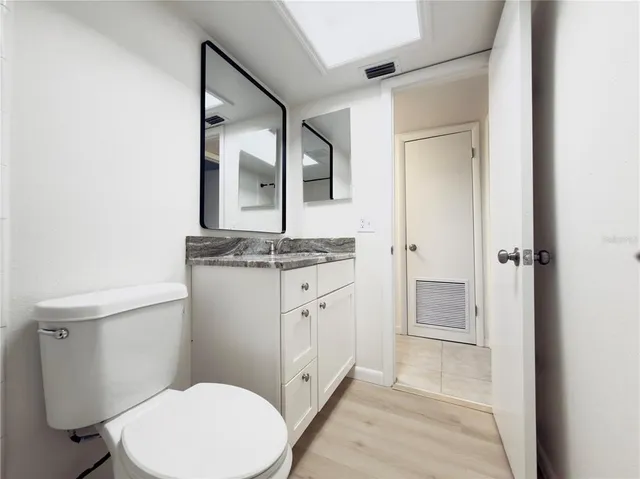a bathroom with a granite countertop toilet sink and mirror