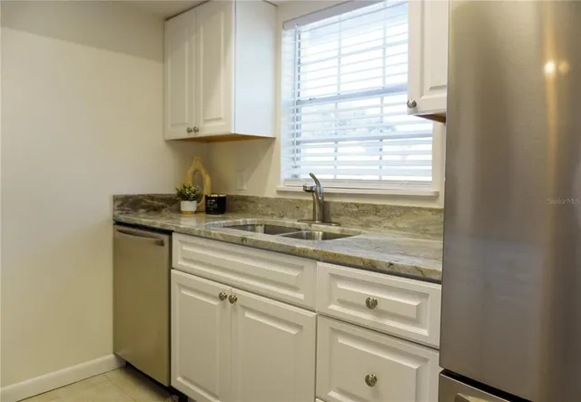 a kitchen with granite countertop white cabinets and white appliances