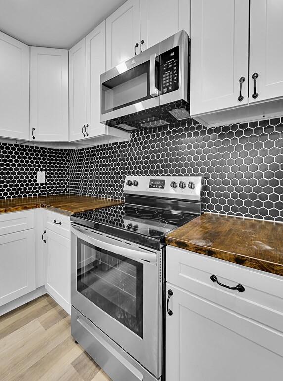 1713 Reuter Avenue Waco, TX 76708 - Photo 11 of 34 Kitchen with stainless steel appliances, butcher block countertops, white cabinets, and backsplash