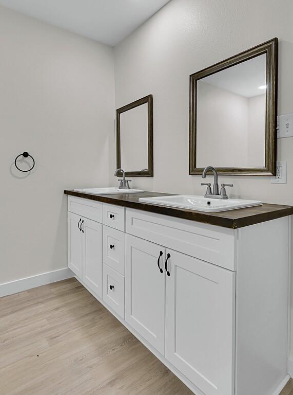 1713 Reuter Avenue Waco, TX 76708 - Photo 17 of 34 Full bathroom with wood finished floors, double vanity, and baseboards