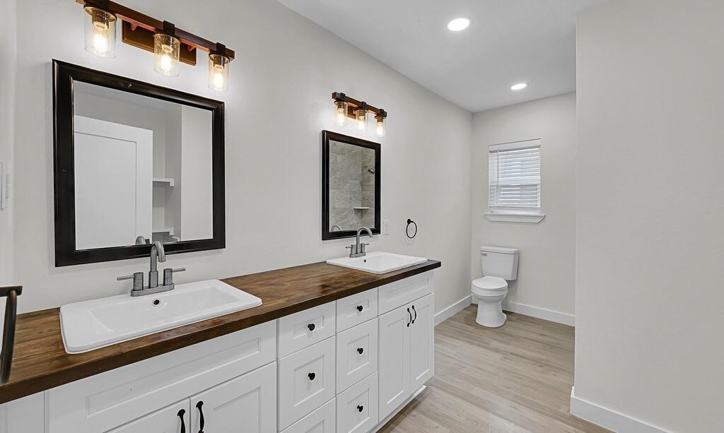1713 Reuter Avenue Waco, TX 76708 - Photo 21 of 34 Bathroom featuring baseboards, toilet, wood finished floors, recessed lighting, and double vanity
