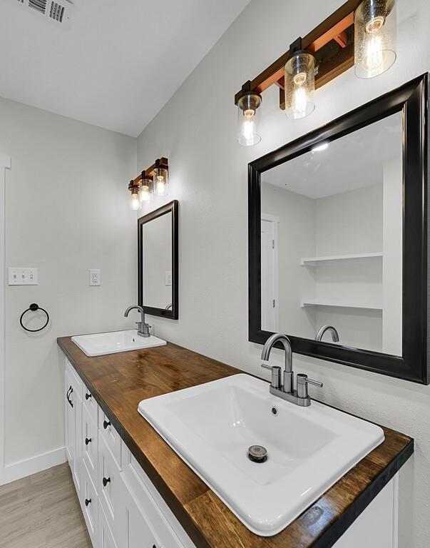 1713 Reuter Avenue Waco, TX 76708 - Photo 22 of 34 Full bath featuring wood finished floors, double vanity, and baseboards