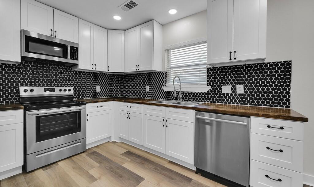 1713 Reuter Avenue Waco, TX 76708 - Photo 9 of 34 Kitchen with appliances with stainless steel finishes, a sink, wooden counters, white cabinets, and decorative backsplash