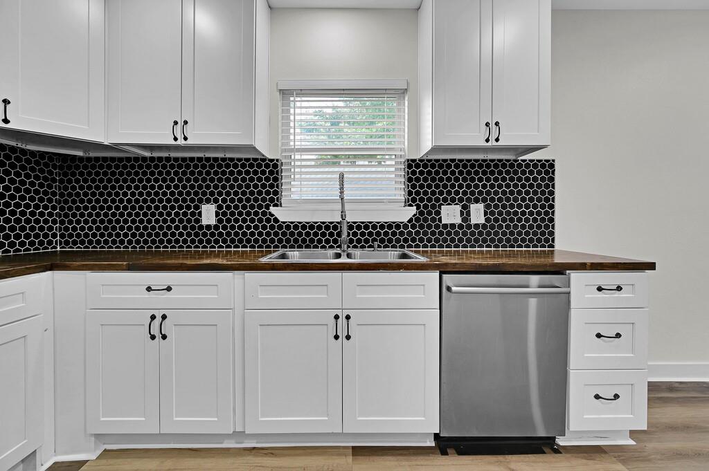 1713 Reuter Avenue Waco, TX 76708 - Photo 10 of 34 Kitchen featuring stainless steel dishwasher, a sink, and white cabinetry