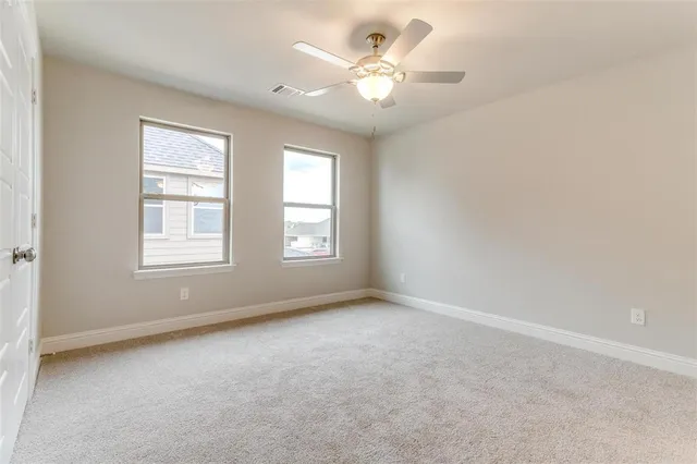 an empty room with windows and ceiling fan