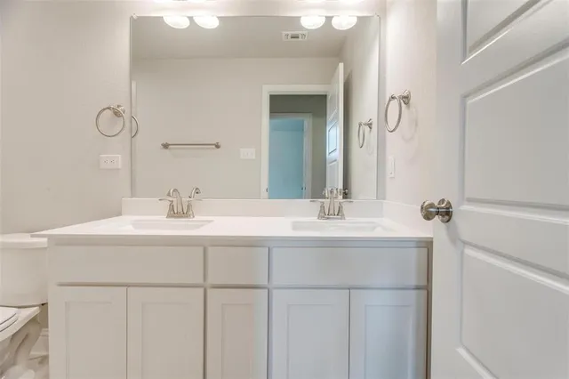 a bathroom with a double vanity sink toilet mirror and bathtub