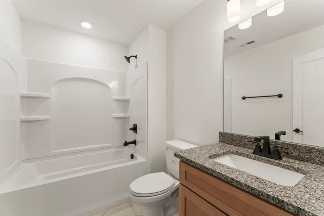 a bathroom with a granite countertop sink a toilet a mirror and shower