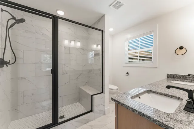 a bathroom with a granite countertop sink a mirror and a shower