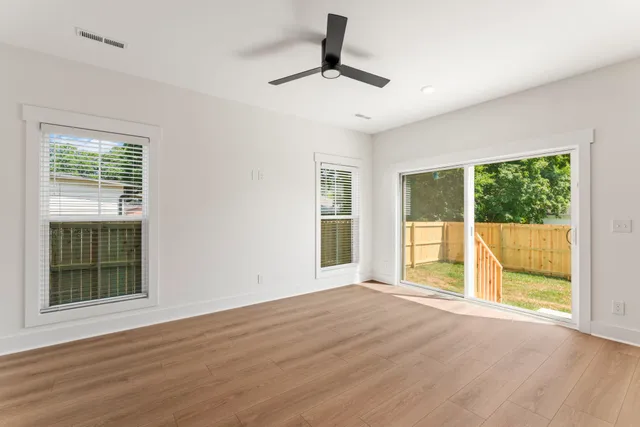 a view of an empty room with a window and wooden floor