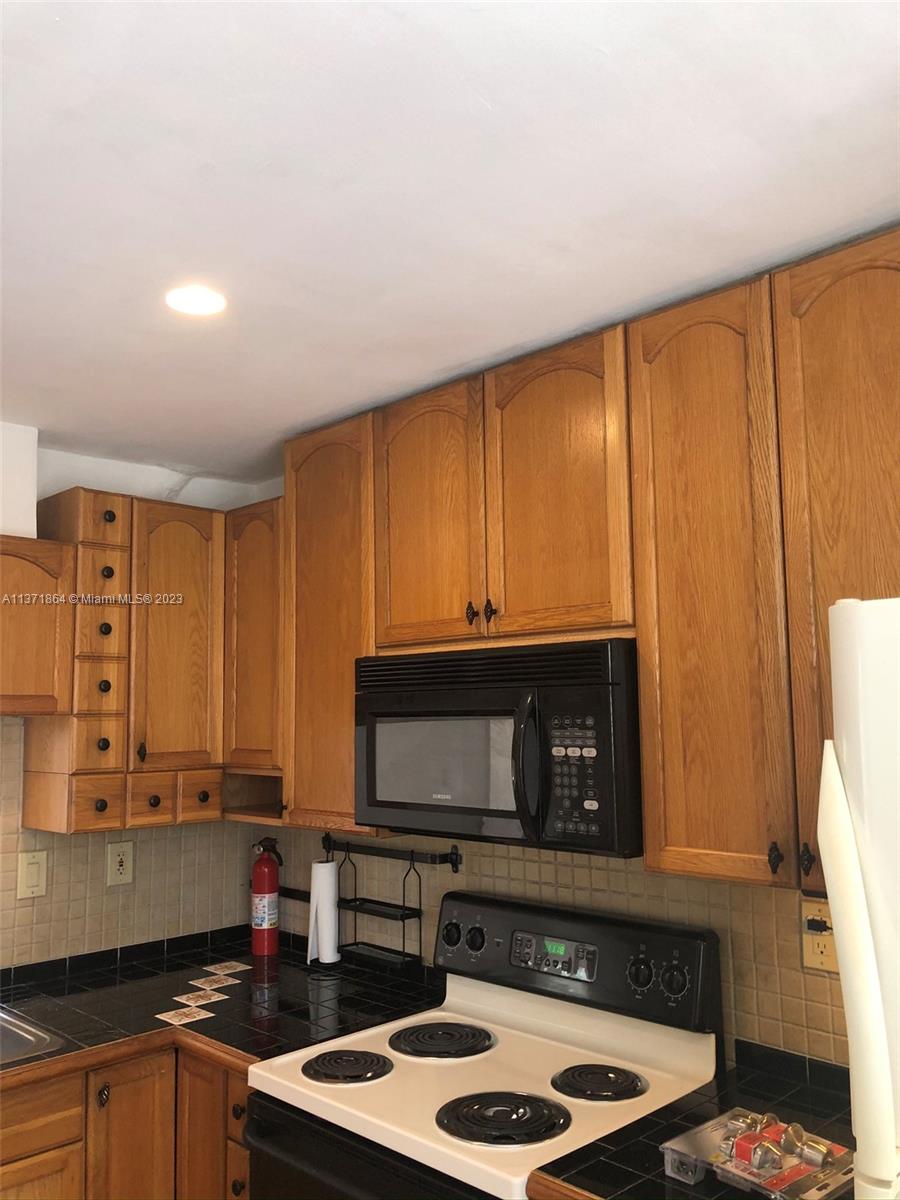 12902 Southwest 88th Terrace, Unit B201 Miami, FL 33186 - Photo 20 of 49 a kitchen with stainless steel appliances wooden cabinets and a stove top oven