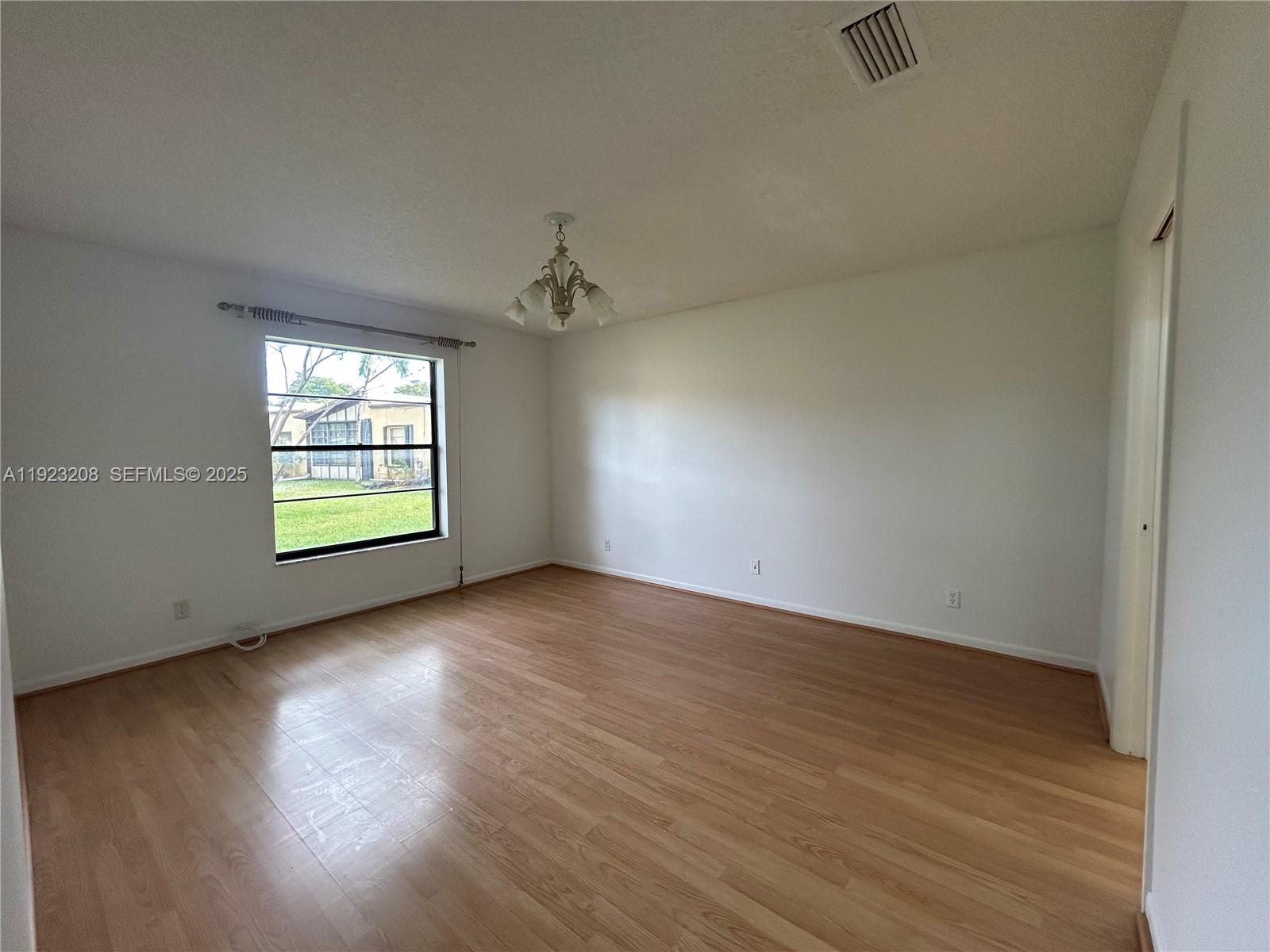 534 Briarwood Circle, Unit 148 Hollywood, FL 33024 - Photo 16 of 40 an empty room with wooden floor chandelier and windows
