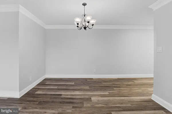 a room with a chandelier and wooden floor