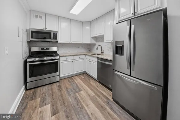 a kitchen with granite countertop a refrigerator stove and microwave