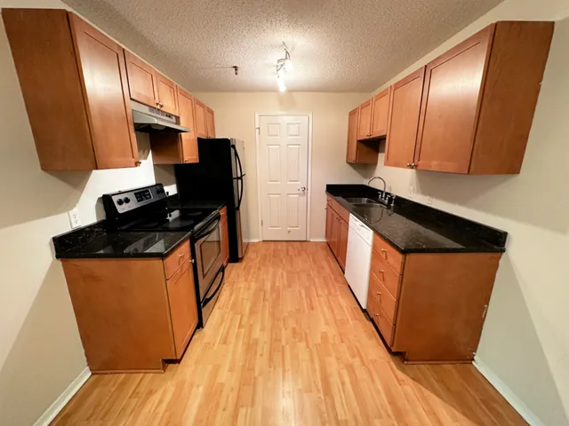 a kitchen with stainless steel appliances granite countertop a stove a sink dishwasher a refrigerator and wooden floor