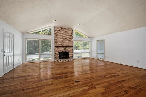 a view of empty room with wooden floor and fireplace