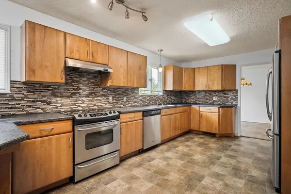a kitchen with granite countertop a sink stainless steel appliances and cabinets