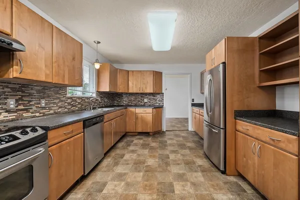 a kitchen with granite countertop a refrigerator stove top oven and sink