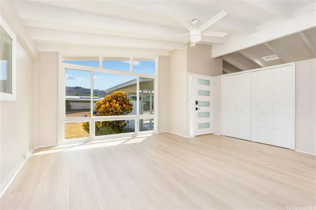 a view of an empty room with a window and kitchen view