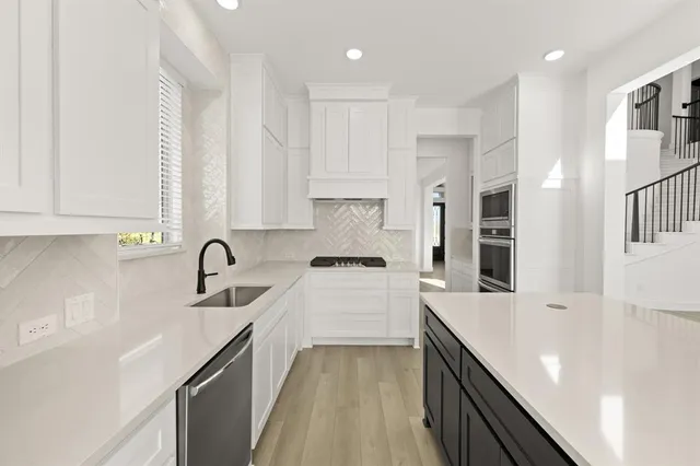 a kitchen with a sink a stove cabinets and a refrigerator