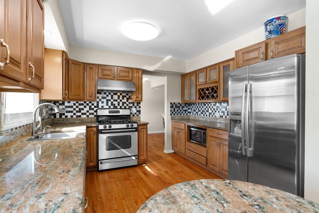a kitchen with granite countertop stainless steel appliances a stove refrigerator and cabinets