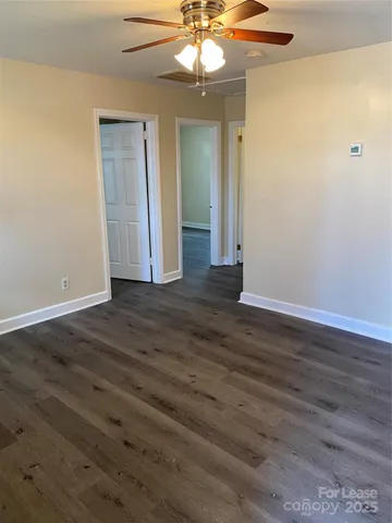 an empty room with wooden floor fan and window